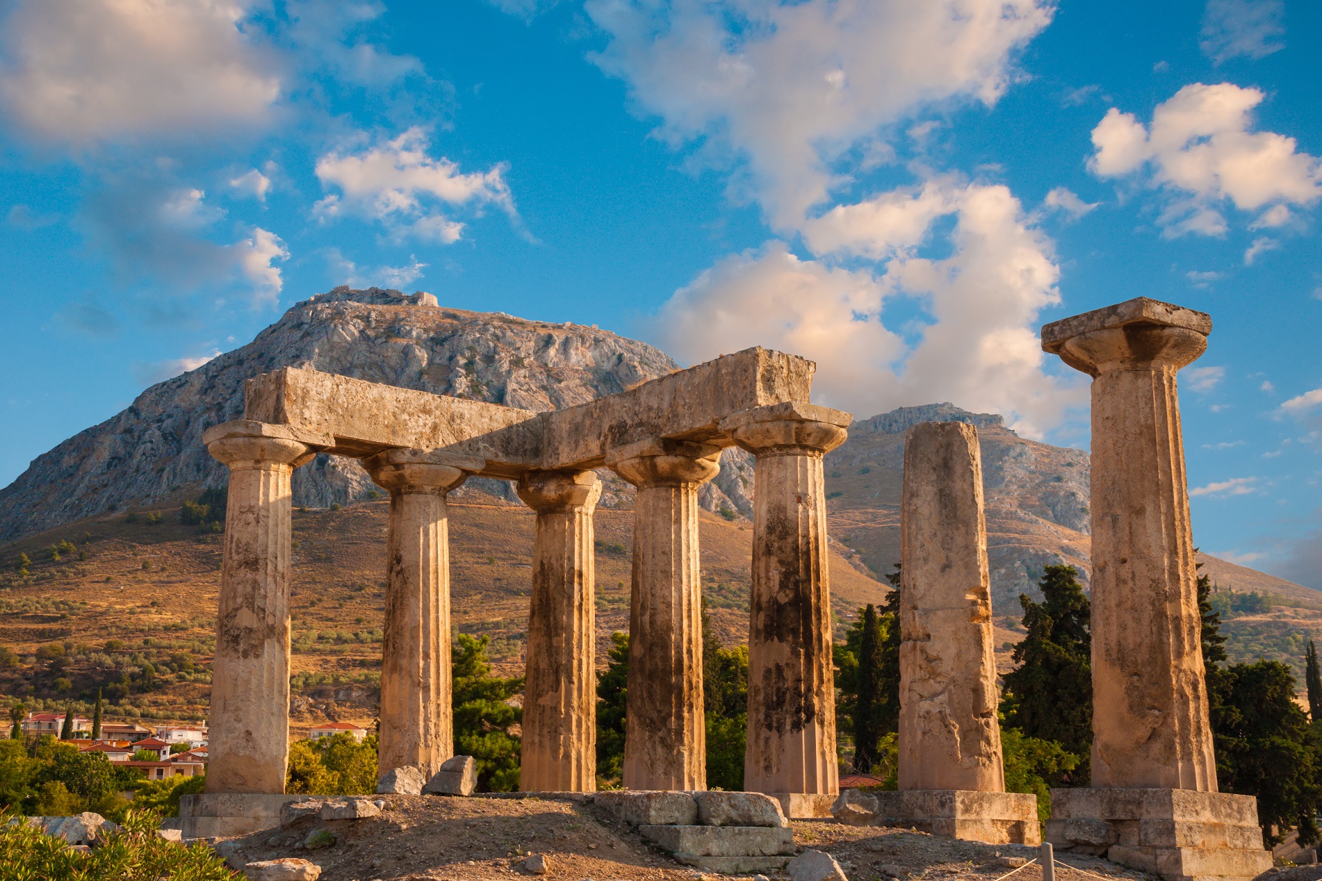 Ruins of Appollo temple with fortress at back in ancient Corinth, Greece